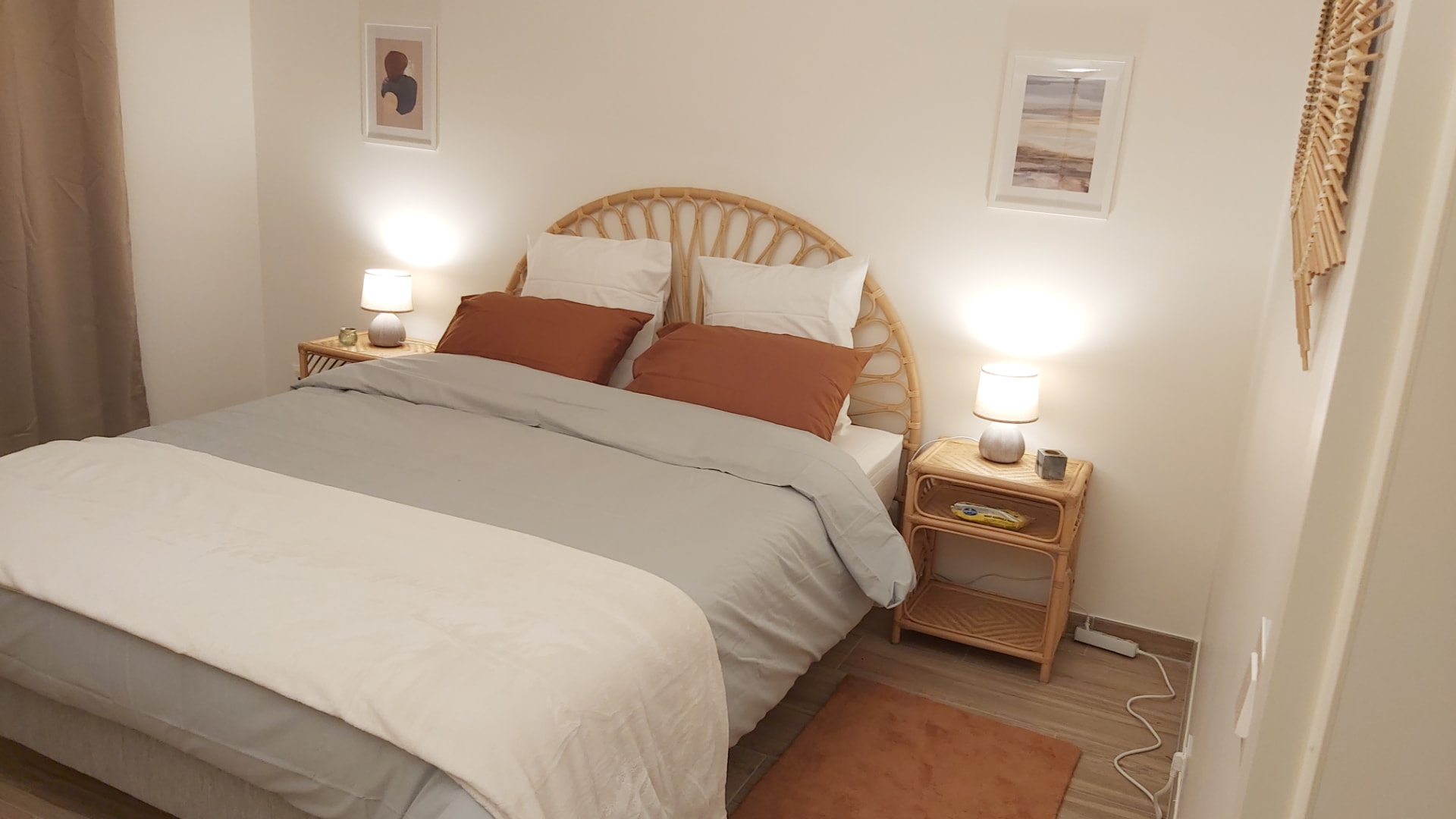 Chambre du Courbevoie lodge avec tête de lit en rotin et coussins terracotta