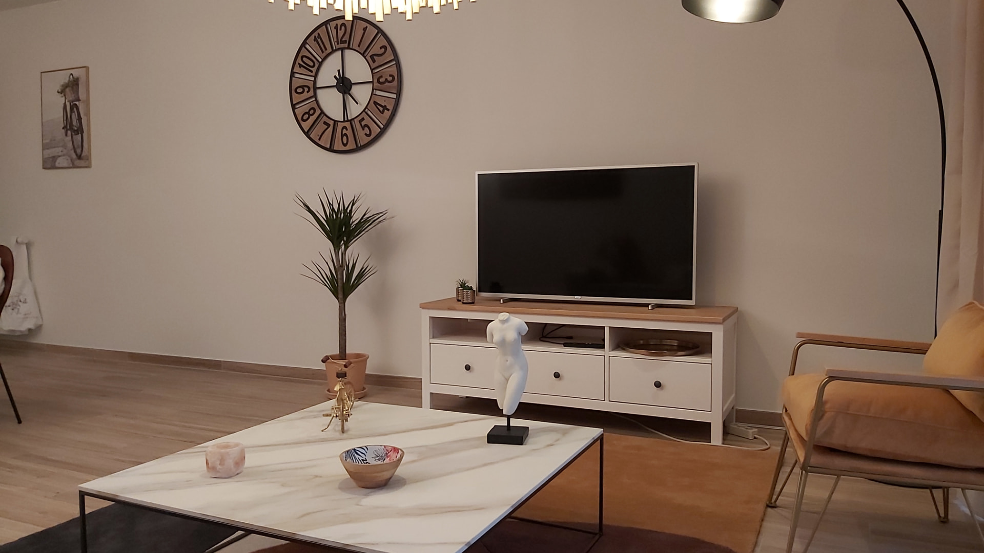 Coin télévision du Courbevoie lodge avec meuble blanc et grande horloge murale
