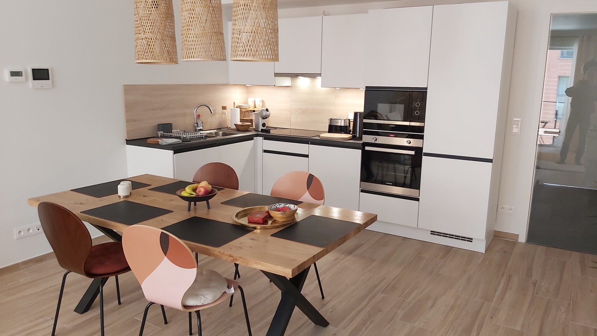 Cuisine équipée du Courbevoie lodge : table en bois, plan de travail, four et micro-ondes encastrés