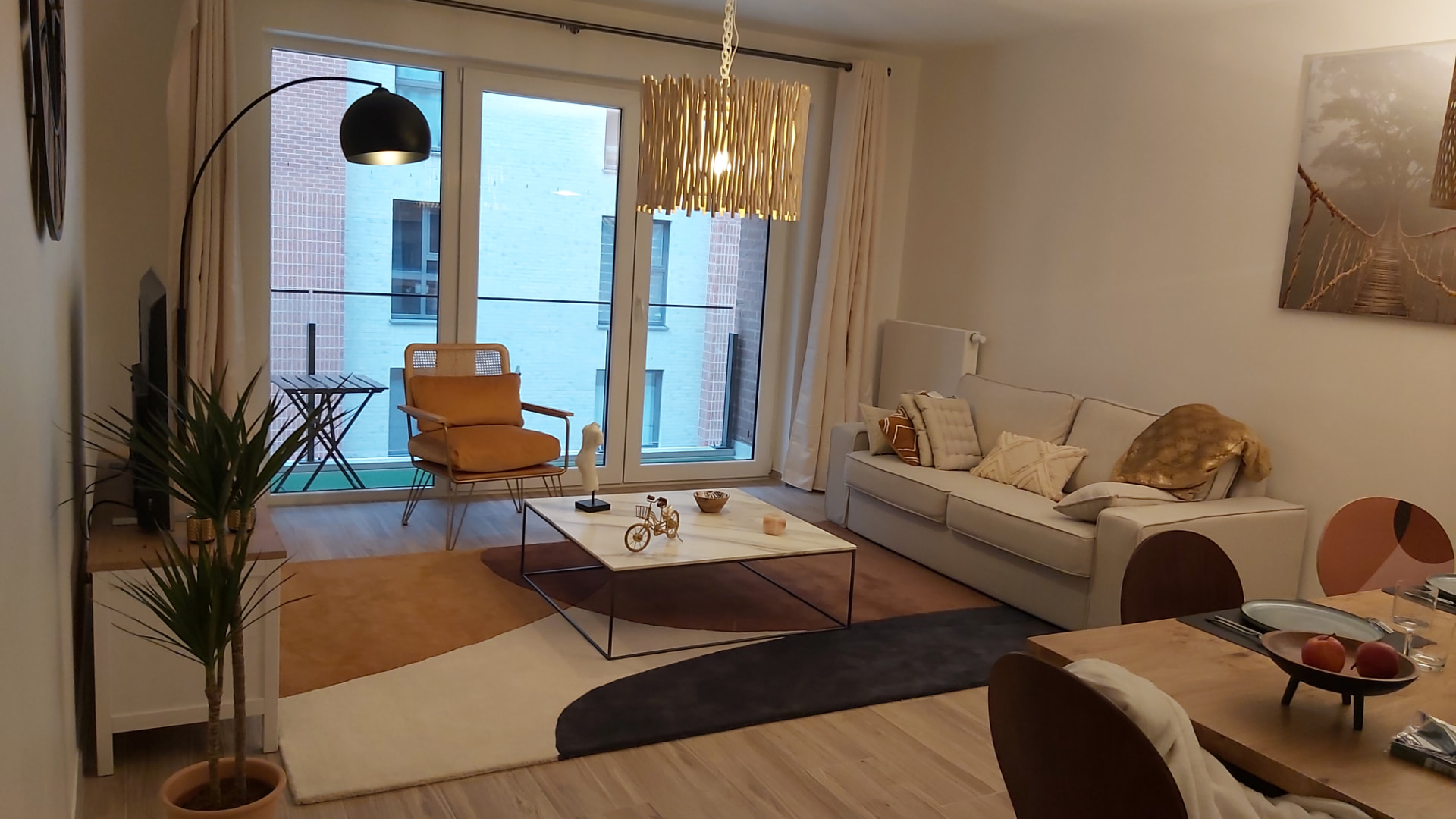 Salon du Courbevoie lodge avec canapé beige, fauteuil ocre et tapis à motifs géométriques